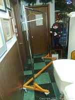 Full view of metal clothes rack showing black vertical poles and orange base with wheels.