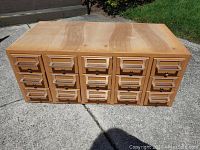 Full front view of the solid wood library cabinet showing 15 drawers arranged in 3 rows and 5 columns, outdoors on concrete.