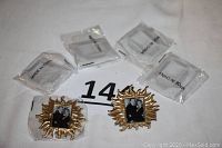 Six mini picture frames by Jay Strongwater wrapped in plastic, gold tone with rhinestone accents, displayed on white fabric.