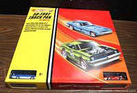 Front view of boxed Hot Wheels 50-foot track pack with visible two cars in window slots and colorful box artwork.