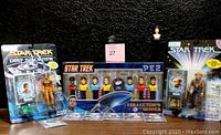 Photo showing 2 Deep Space Nine action figures in original packaging flanking the PEZ Collector's Series boxed set of 10 Star Trek character busts.