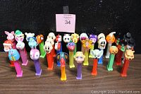 Front view of 32 assorted vintage PEZ dispensers arranged in a row showing multiple colors and character heads.