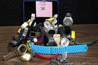 Overview of 21+ assorted watches arranged on a table showing diversity in straps and watch faces