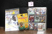 Photo of the sealed Pinnacle price guide with a football player on the cover, the carded Reggie White figure, and the binder with trading cards inside.