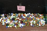 Wide view of assorted marbles spread out on a surface showcasing colors, sizes, and styles