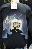 Front view of black sweatshirt on mannequin showing colorful Disney graphic with Tinkerbell, vintage TV, and Disney logo.