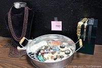 Photo showing vintage decorative buttons in a round metal tin, three brown bead necklaces draped on a black velvet neck display, and four watches displayed upright including a Timex watch and Renaissance Quartz watch with stone watchband.