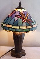 Full frontal shot of lamp lit showing entire stained glass shade and metal base