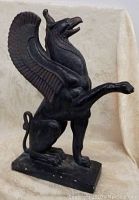 Front view of black griffin/gargoyle statue perched on rectangular base