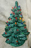 Front view of ceramic Christmas tree lamp showing multicolored lights on tree branches.