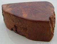 Closed triangular burled wood trinket box showing natural wood grain and knots on outer surface.