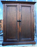 Front view of oak wood small wardrobe case with two paneled doors and round knob pulls