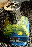 Close-up of the decorative metal cap with floral cutouts on top of the porcelain lamp