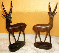 Pair of carved wood antelope statues front view showing long horns and smooth finish.