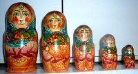 Front view of five Russian nesting dolls with colorful hand-painted faces and floral scarves, arranged in descending size order.