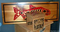 Rectangular wooden Haida plaque with red and black traditional animal design and signed by Corey Bullpit.