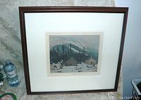 Framed print on table with water bottle beside for size reference.
