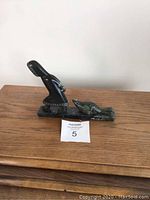 Front view of indigenous stone carving showing the figure and smaller animal on the base, signed on the side.