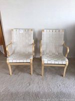 Front view of two chairs side by side showing woven white webbing and bentwood frames