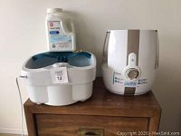 Footbath, humidifier, and a bottle of water treatment solution placed on wooden cabinet.