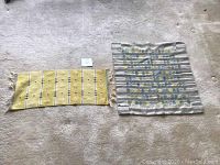 Two wool wall hanging tapestries laid flat on carpet, showing relative size and pattern details.