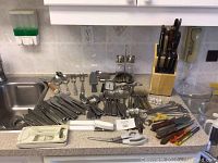 Wide view of all assorted utensils and knife block arranged on countertop, showing the quantity and variety of items.
