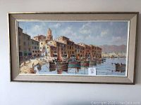 Full frontal view of framed painting showing coastal buildings and boats