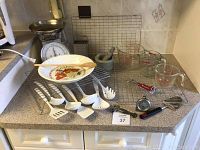 Overall view of kitchen counter with kitchen scale, measuring cups, cooling racks, utensils, grater, mortar and pestle, and plate