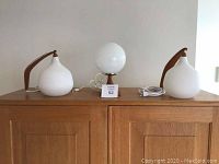 Front view of two wall lamps flanking desk lamp on wooden surface