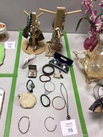Photo of lot items arranged on table showing bracelets, necklaces, earrings, rings, eyeglasses and decorative items.