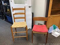 Two accent chairs on carpeted floor, one with woven seat and ladder back, the other with solid wood and red cushion