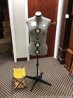 Front view of adjustable dress form on tripod stand with folding stool at base