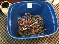 Blue plastic bin containing multiple metal C-clamps and plastic spring clamps, showing different sizes and slight wear.
