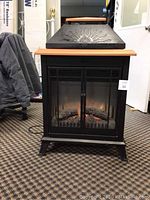 Front view of black Dimplex electric fireplace with mesh screen door and flame effect seen inside.