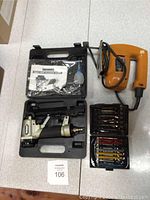 Photo showing the pneumatic staple gun in case with manual and accessories, orange scroll saw, and two sets of scroll saw blades.