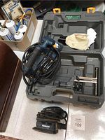 Overview of the hand planer and palm sander placed in and near the hard plastic carrying case, including a dust collection bag.