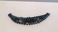 Curved vintage bracelet with blue rhinestones on dark metal base, showing overall design and color.