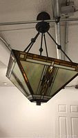 Front view of pendant lamp showing geometric stained glass shade and metal rods