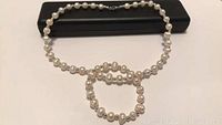 Pearl necklace and matching bracelet laid flat, showing overall length and pearl detail.