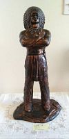 Photo of the ceramic figure showing a Native American man statue with bronze paint and detailed headdress.