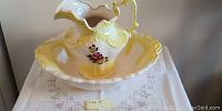Photo of ceramic water jug sitting inside the basin showing floral design and yellow-cream gradient