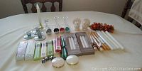 Wide shot of assortment laid out on table showing variety of candle holders, candles, and decorative items.