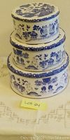 Three stacked blue and white scenic ceramic cookie tins of varying sizes.