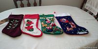 Four Christmas stockings lined up on a white surface showing all designs and colors.