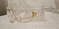 Clear crystal decorative sleigh with gold ribbon bows and chain connecting reindeer to sleigh