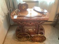 Front view of wooden tea cart with decorative floral inlay, drop leaves folded down