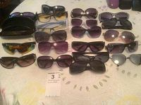 Photo showing an array of 16 women's sunglasses in various styles and frame colors laid out on a light surface.