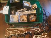 Assorted costume jewelry in green tote including bracelets, earrings and bead necklaces