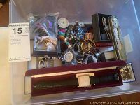 Photo of assorted watches laid inside a plastic container including leather strap and metallic watches.