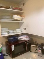 RCA microwave, toaster, coffee grinder, various dishes and kitchenware in cabinet and on counter